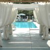 Un gazebo con tende bianche accanto a una piscina.