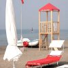 Spiaggia con una torretta di salvataggio, sdraio e ombrelloni.
