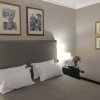 Stanza d'albergo con letto matrimoniale, cuscini bianchi e quadri appesi sopra.