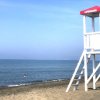 Spiaggia con torretta bianca di salvataggio e mare azzurro sullo sfondo.