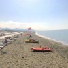 Spiaggia sabbiosa con lettini e ombrelloni, pedalò colorati.