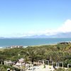 Vista panoramica del mare con montagne in lontananza e vegetazione in primo piano.