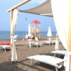Spiaggia con lettini, tende bianche e torretta di guardia.