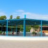 Un'ampia struttura circolare con un tetto blu, circondata da alberi e piante.