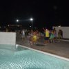 Un gruppo di persone balla all'aperto vicino a una piscina illuminata di notte.