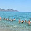 Persone in mare formano una catena sorridente.
