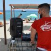 Una persona con una maglietta rossa gestisce l'attrezzatura audio su una spiaggia affollata.