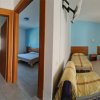 Una camera d'albergo con due letti singoli e una porta aperta verso un'altra stanza.
