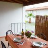 Tavolo da pranzo all'aperto apparecchiato per quattro persone con una bottiglia di vino e fiori.