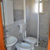 Bagno con doccia, WC, bidet e lavandino con piastrelle grigie.