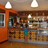 Interno di un bar con decorazioni floreali, una persona serve al bancone, una bambina attende.