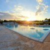 Piscina triangolare all'aperto con lettini, al tramonto, cielo blu con nuvole.