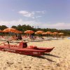 Una spiaggia con una barca di salvataggio rossa e file di ombrelloni giallo-arancioni.