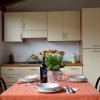 Cucina con tavolo apparecchiato, piatti, bicchieri, una bottiglia di vino e un vaso di fiori.