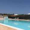 Una piscina all'aperto con lettini, ombrelloni e cielo sereno.