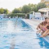 Famiglia seduta a bordo piscina, con i piedi nell'acqua.