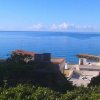 Vista sul mare con case bianche e vegetazione in primo piano.