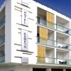 Albergo moderno con ampie balconate e vetrate, cielo blu sullo sfondo.