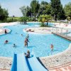 Piscina all’aperto con scivolo e persone che nuotano.