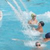 Persone che nuotano in piscina con getti d'acqua.