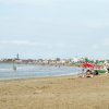 Una spiaggia con persone, sedie a sdraio e ombrelloni.