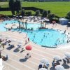 Piscina affollata con ombrelloni e lettini.