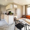 Una cucina moderna e luminosa con tavolo apparecchiato e divano arancione.