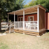 Un bungalow con veranda in legno e sedie bianche.