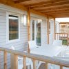 Veranda di legno con sedie e tavolo bianco.