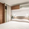 Letto matrimoniale in una camera moderna con testiera imbottita e armadio a muro.