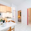 Cucina luminosa con tavolo apparecchiato. Due stanze sullo sfondo con porte rosse.