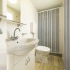 Bagno compatto con doccia, lavabo bianco e WC. Dettaglio su superfici chiare.