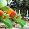 Persona su uno scivolo acquatico verde a spirale che scende in piscina. Ombrelloni sullo sfondo.