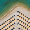Ombrelloni gialli disposti a fila su una spiaggia, vicino a un mare turchese.