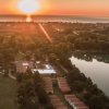 Tramonto su un paesaggio con lago, case e alberi, riflesso sull'acqua.