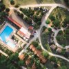 Vista aerea di un complesso con piscine, strade e casette immerse nel verde.
