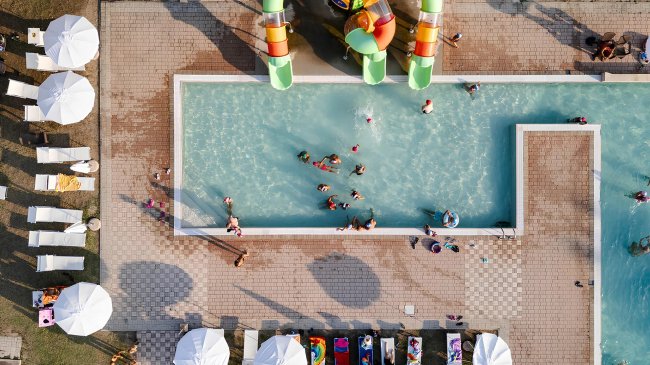 Piscina rettangolare con bambini e scivoli.