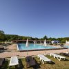 Piscina all'aperto con lettini e ombrelloni bianchi su prato.