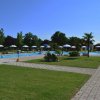 Piscina circondata da ombrelloni e palme, con sentiero in mattoni.