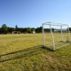 Un campo da calcio con porte su un prato verde e cielo sereno.