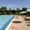 Una piscina all'aperto con lettini e ombrelloni bianchi lungo il bordo.