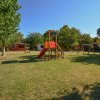 Area giochi per bambini con altalene e scivolo su un prato.