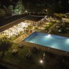 Vista notturna di una piscina illuminata con persone riunite a un evento vicino.