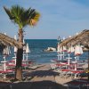 Spiaggia con ombrelloni di paglia e lettini rossi, vista sul mare.