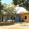 Villini colorati tra gli alberi con tavoli e sedie bianche all'esterno.