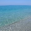 Spiaggia con ciottoli e mare azzurro.