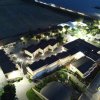 Vista aerea di un complesso residenziale illuminato di notte vicino al mare.