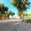 Vialetto pavimentato tra alberi e giardino con strutture gialle.