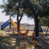 Parco giochi con scivolo e altalene tra alberi.