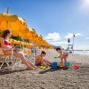 Spiaggia con ombrelloni gialli e bambini che giocano.